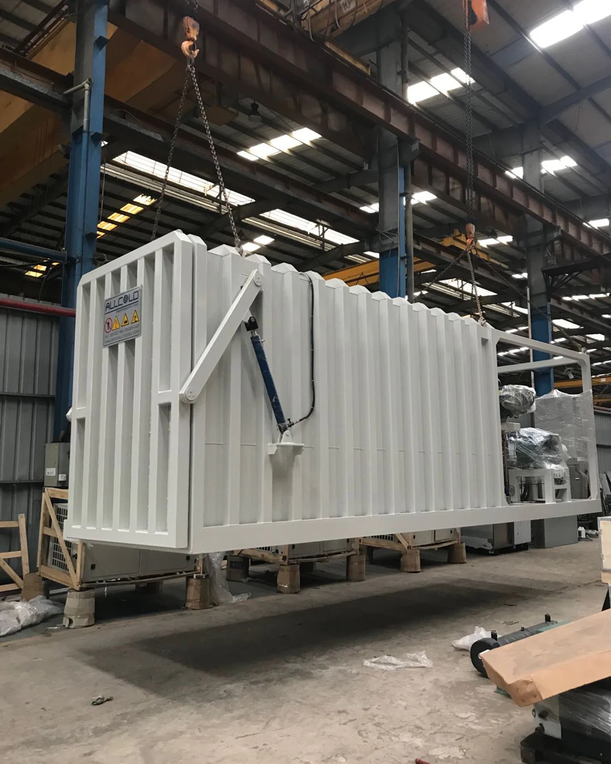 Real painted Allcold vegetable vacuum cooler under assembly showing the ribbed chamber, outward-opening door structure and rear equipment frame