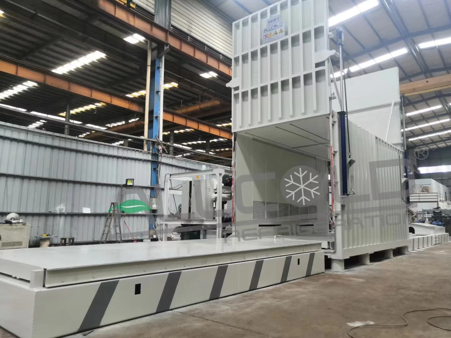 Allcold produce vacuum cooler with raised vertical-lift door and adjacent equipment frame in the factory