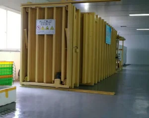 Yellow Allcold vacuum cooling chamber installed inside a produce handling building, with green crates alongside