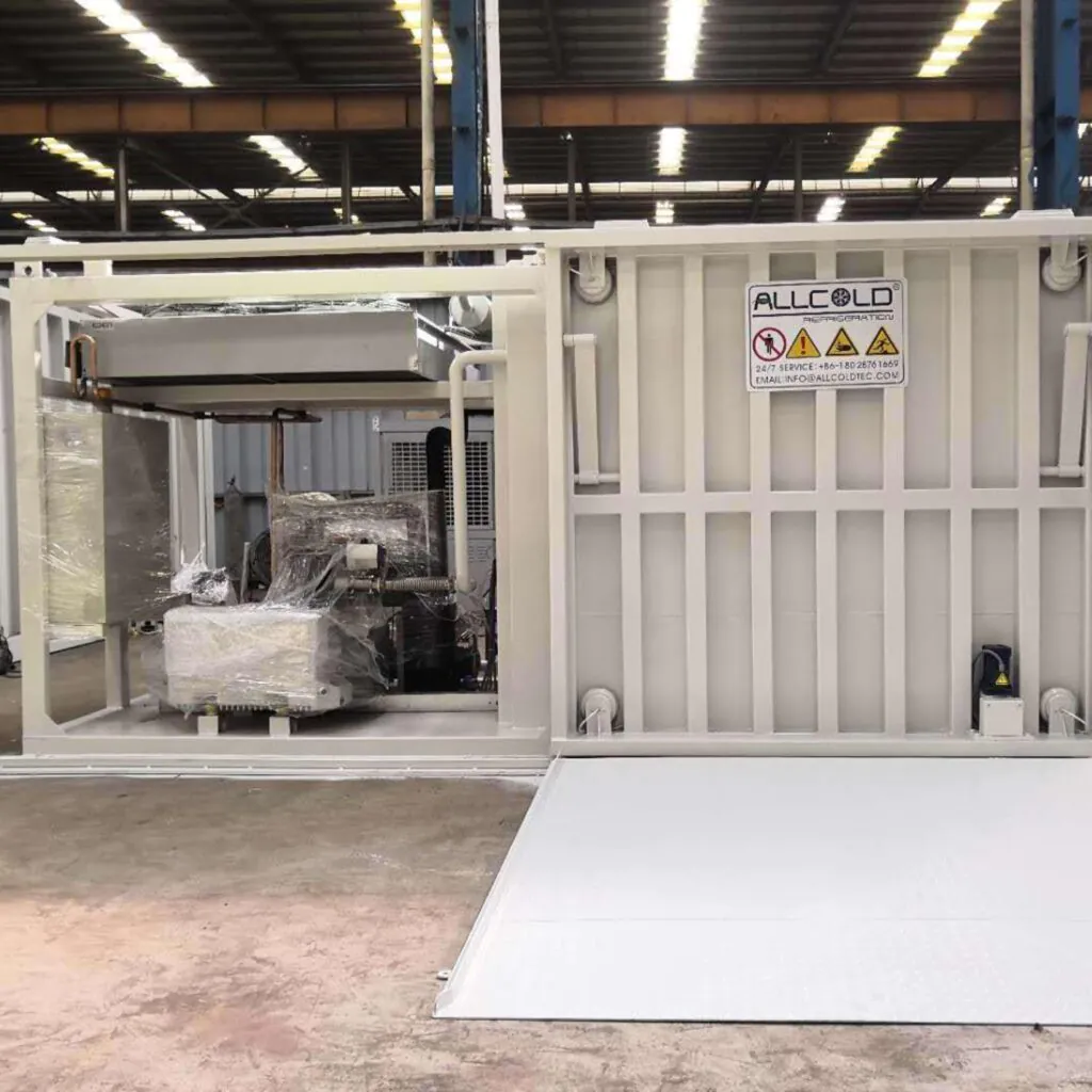 Vacuum cooling unit made of carbon steel, shown in an open industrial workshop. The chamber is open to reveal internal components including the refrigeration system and control panel. Labeled with the Allcold logo and safety signage.