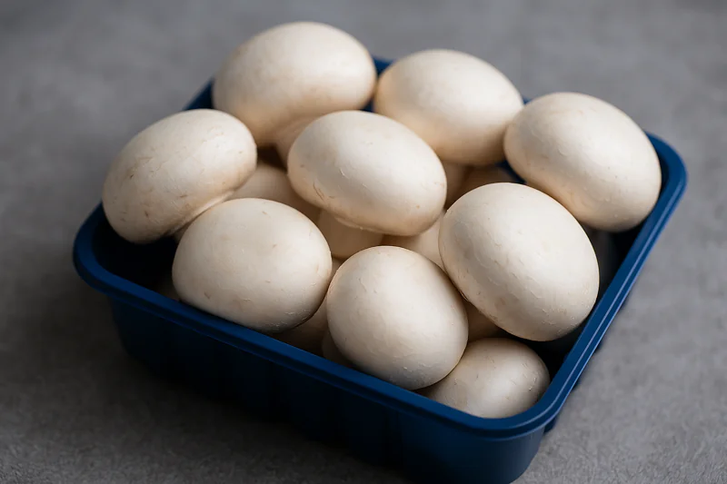 A stunning close-up of pristine white mushrooms in a punnet, looking firm and fresh, post-vacuum cooling.