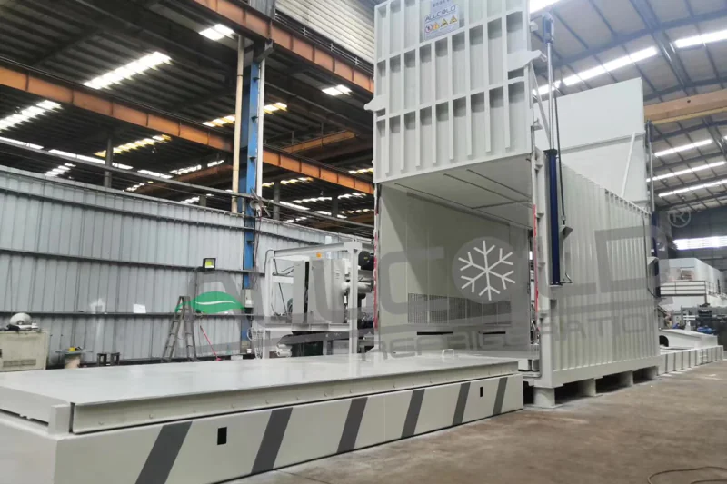 A photo of an ALLCOLD vacuum cooler with an automated power roller conveyor system leading into its door.