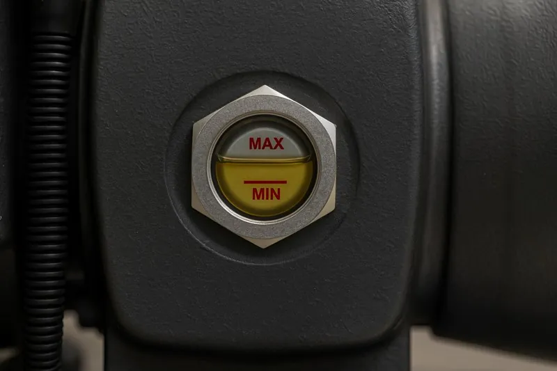 A close-up shot of an operator's sight glass on a vacuum pump, with the oil level perfectly in the middle of the marked range.