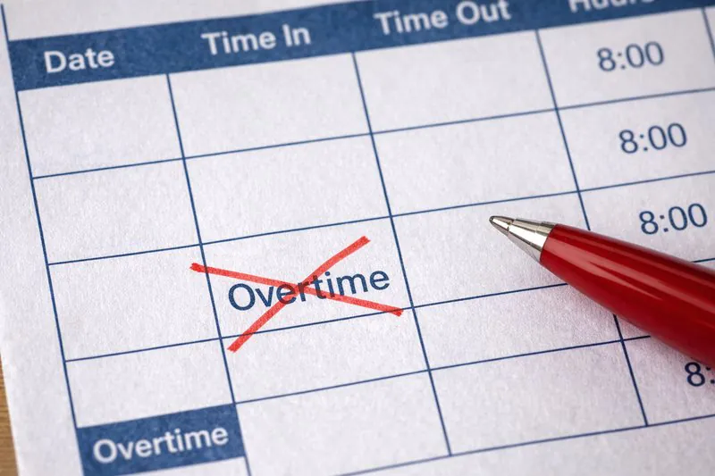 A photo of a timecard or payroll sheet with 'Overtime' crossed out in red ink.