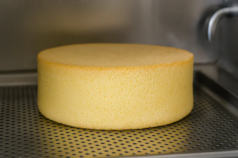 A close-up photo of a fluffy sponge cake inside a vacuum chamber, retaining its full height and structure.