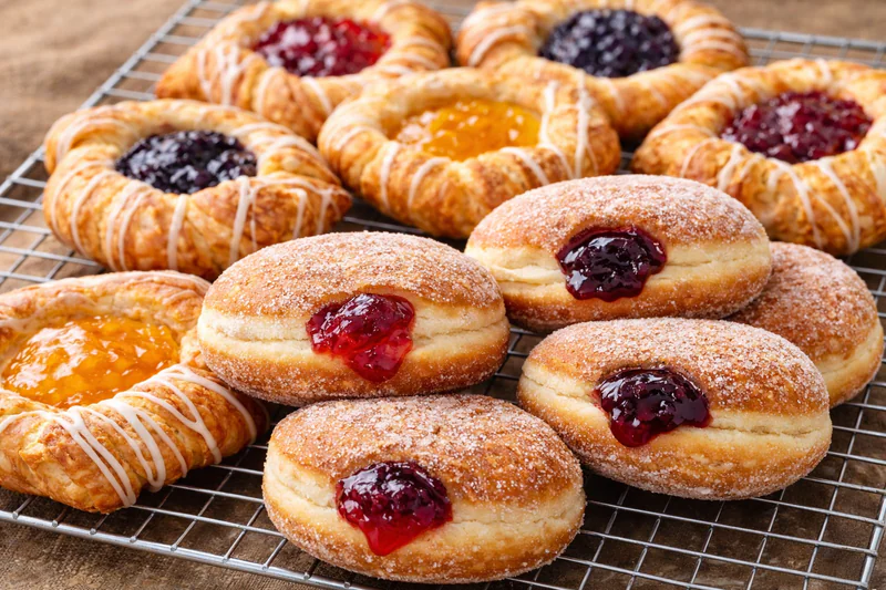 jam filled donuts and pastries on a cooling rack
