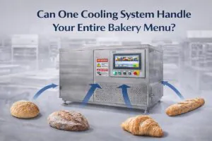 Horizontal graphic of a stainless steel vacuum cooling system in a modern bakery, with bread, baguette, croissant and other baked products around it, showing one cooling solution for an entire bakery menu